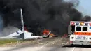 Mobil ambulans berada dekat lokasi jatuhnya sebuah pesawat kargo militer Amerika Serikat di jalan raya dekat bandara Savannah, Georgia, Rabu (2/5). Pesawat C-130 Hercules tersebut jatuh lalu meledak menimbulkan bola api yang besar. (James Lavine via AP)