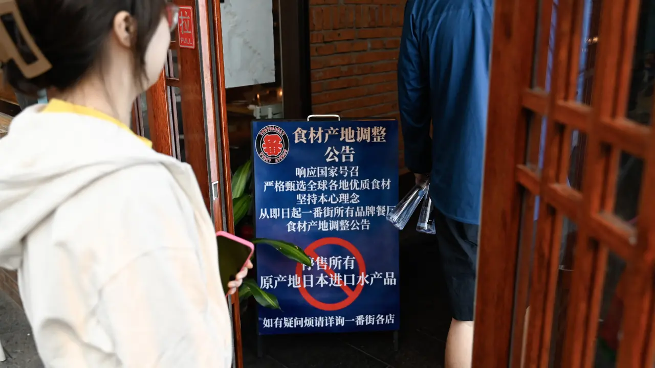 Orang-orang berjalan ke area restoran Jepang melewati papan bertuliskan "Tangguhkan penjualan semua produk ikan yang diimpor dari Jepang", di Beijing pada 27 Agustus 2023.