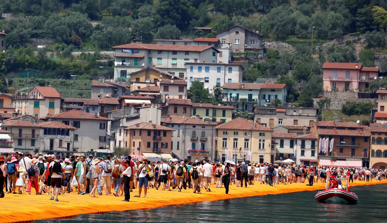 Sejumlah wisatawan berjalan di atas instalasi "The Floating Piers" karya Christo Vladimirov Javacheff di Danau Iseo, Italia, (24/6). Proyek seni instalasi ini telah menghabiskan biaya USD 16,7 juta atau sekitar Rp 224 miliar. (REUTERS/Stefano Rellandini)
