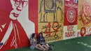 Dua orang wanita duduk di dekat mural yang dibuat oleh seniman Shepard Fairey di kawasan Wynwood, Miami, Florida pada 28 September 2016. Goldman Properties menggelar pameran mural untuk merevitalisasi lingkungan. (AFP PHOTO / Rhona WISE)