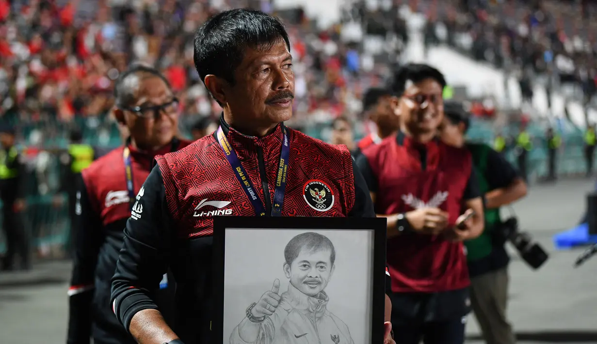 Pelatih kepala Timnas Indonesia U-22, Indra Sjafri memegang gambar dirinya saat merayakan kemenangan pada laga final sepak bola SEA Games 2023 melawan Thailand di Olympic Stadium, Phnom Penh, Kamboja, Selasa (16/05/2023). Skuad Garuda Nusantara menang dengan skor 5-2. (AFP/Nhac Ngyuen)