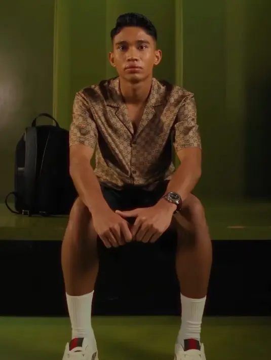 Look kedua, ia pun bergaya fancy mengenakan kemeja lengan pendek warna coklat dengan ciri khas logo Gucci. Dipadukan kaos kaki dan sneakers putihnya. [@kacastuudio]