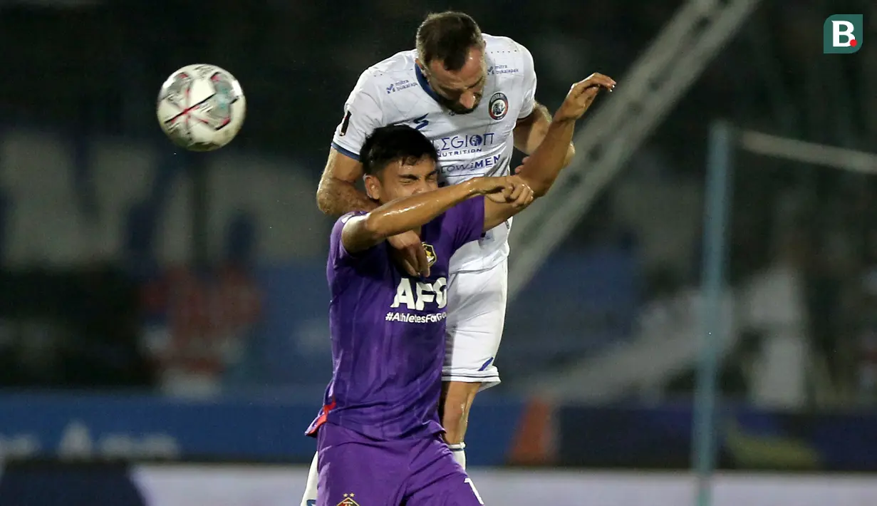 Pemain Persik, Muhammad Ridwan (bawah) berduel udara dengan pemain Arema FC, Sergio Domingos Reis Silva dalam lanjutan pertandingan babak penyisihan Grup D Piala Presiden 2022 antara Persik Kediri menghadapi Arema FC di Stadion Kanjuruhan, Malang, Jawa Timur, Rabu (15/6/2022). (Bola.com/Arief Bagus)