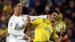 Bintang Real Madrid, Cristiano Ronaldo, berebut bola dengan bek Las Palmas, Pedro Bigas. Kemenangan ini membuat Real Madrid terus membuntuti Atletico Madrid di peringkat ketiga klasemen La Liga. (Reuters/Juan Medina)