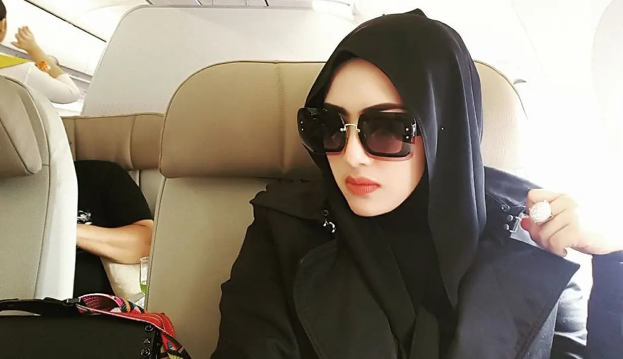 Perempuan berkulit putih ini sepertinya tak lepas dari kacamata hitamnya. Dan begitu juga dengan penampilannya di foto ini yang memakai outfit serba hitam mulai dari busana hingga hijabnya. (Doc.Facebook)