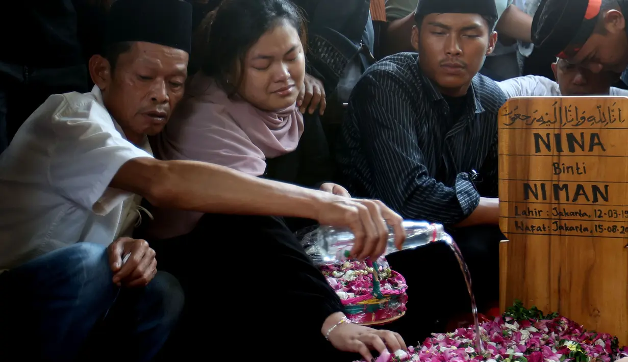 Kerabat menabur bunga di makam presenter sekaligus komedian Nina Carolina atau yang akrab dipanggil Mpok Alpa di Tempat Pemakaman Umum (TPU) Kujaran, Ciganjur, Jakarta Selatan pada Jumat (15/8/2025). (KapanLagi.com/Budy Santoso)
