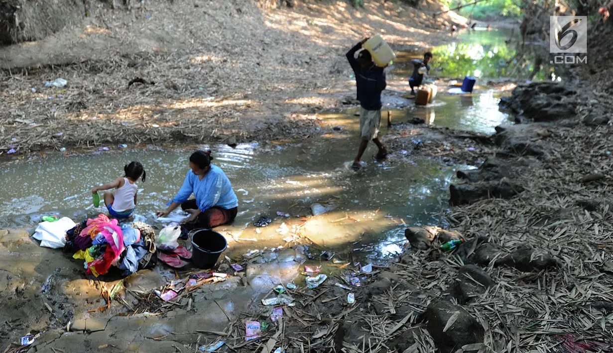 Warga mencuci pakaian dengan air dari lubang pada aliran Sungai Cihoe yang digunakan untuk memenuhi kebutuhan sehari-hari di Ridogalih, Cibarusah, Bekasi, Minggu (7/7/2019). Sudah lebih dari dua bulan, warga memanfaatkan sisa aliran sungai yang kotor akibat musim kemarau. (merdeka.com/Arie Basuki)