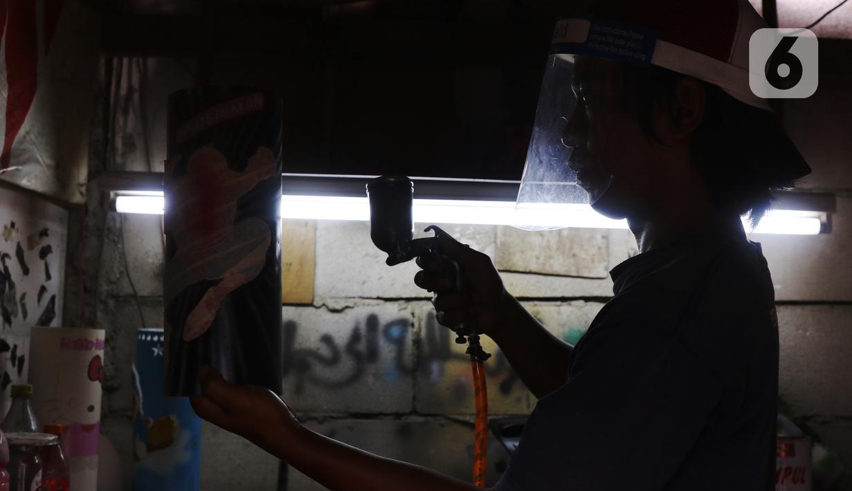Perajin menyemprotkan cat pada proses pembuatan lampu hias berkarakter dari bahan pipa di Tangerang, Selasa (5/1/2021). Lampu hias berkarakter tersebut dijual dikasaran harga Rp 100 hingga Rp 150 ribu tergantung tingkat kesulitan. (Liputan6.com/Angga Yuniar)