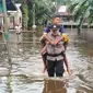 Personel Polres Rokan Hilir menggendong anak-anak korban banjir untuk mempermudah mobilitas warga. (Liputan6.com/M Syukur)