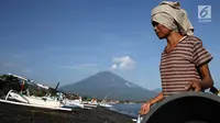 Nelayan membawa hasil tangkapannya dengan latar Gunung Agung di kawasan Amed, Karangasem, Bali, Kamis (7/12). Sepekan terakhir, aktivitas Gunung Agung mulai tampak tenang, meskipun masih status Awas. (Liputan6.com/Immanuel Antonius)