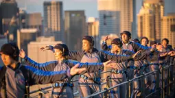 Anggota akademi Tai Chi dan Qigong Australia melakukan latihan Tai Chi di atas Jembatan Sydney Harbour, Australia, Selasa (2/5). Demi keselamatan, mereka dilengkapi tali pengaman yang dikaitkan di pagar besi. (Handout / BRIDGECLIMB SYDNEY / AFP)