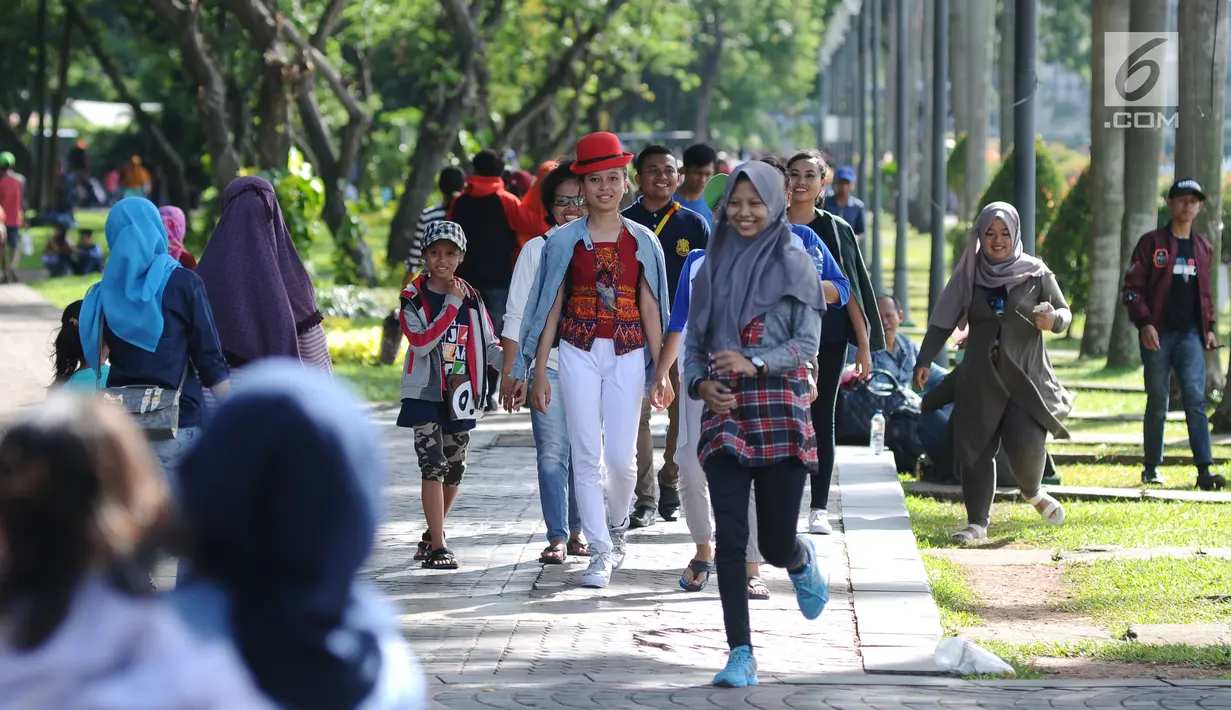 Pengunjung berjalan di kawasan Monumen Nasional, Jakarta, Senin (25/12). Libur perayaan Natal dimanfaatkan warga untuk berwisata di kawasan Monumen Nasional. (Liputan6.com/Helmi Fithriansyah)