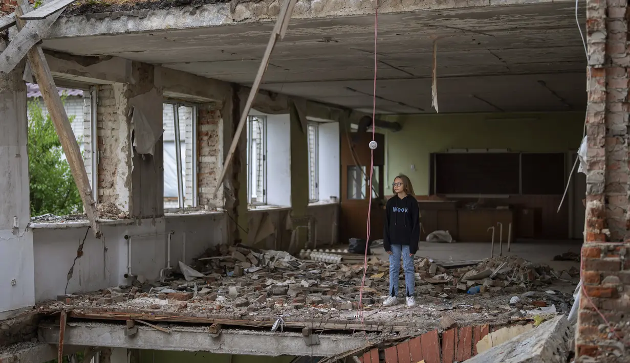 Anna Skiban (12) berdiri di puing-puing bekas ruang kelasnya, di posisi yang sama di mana mejanya duduk di depan bacaan Mykhailo-Kotsyubynske yang dibom oleh pasukan Rusia pada 4 Maret, di Chernihiv, Ukraina, Selasa, 30 Agustus 2022. Banyak sekolah Ukraina dibuka kembali pada 1 September untuk pertama kalinya sejak invasi Rusia dimulai pada 24 Februari lalu. (AP Photo/Emilio Morenatti)