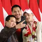 Erick Thohir (kiri) dan&nbsp;Menteri Pemuda dan Olahraga Dito Ariotedjo foto bersama dengan Rizki Juniansyah pada saat di&nbsp;Bandara Internasional Soekarno-Hatta, Tangerang, Selasa (13/8/2024). (Abdul Aziz/Bola.com).