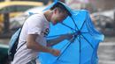 Seorang pria memegang payung sambil berjalan menghindari angin kencang yang disebabkan topan Dujuan di Taipei, Taiwan, Senin (28/9). Ribuan orang diungsikan untuk menghadapi topan Dujuan yang diprediksikan akan menyerang Taiwan. (REUTERS/Pichi Chuang)