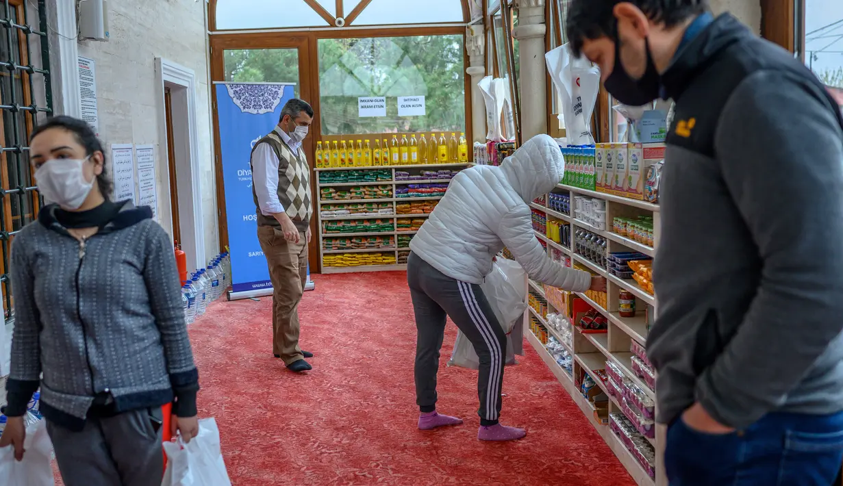 Orang-orang mengambil kebutuhan mereka di rak-rak sepatu di masjid Dedeman di distrik Sariyer, Istanbul pada 21 April 2020. Jelang Ramadan, masjid itu membuka supermarket gratis yang menyediakan kebutuhan sehari-hari secara gratis untuk warga membutuhkan yang terdampak Corona. (Bulent Kilic/AFP)