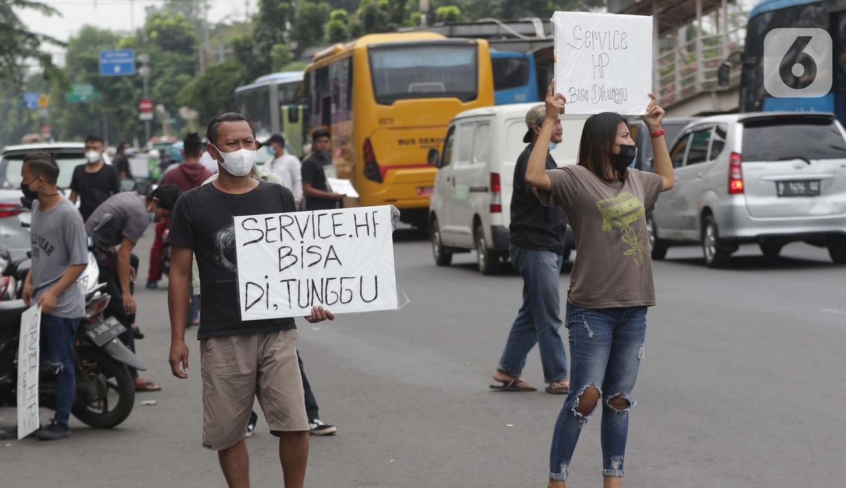 Penjual jasa perbaikan telepon genggam menawarkan jasa di pinggir jalan Mayjen Sutoyo depan Mall Pusat Grosir Cililitan (PGC), Jakarta, Rabu (14/7/2021). Kios yang biasa mereka tempati tutup seiring penutupan Mall PGC selama pemberlakuan PPKM Darurat Jawa-Bali. (Liputan6.com/Helmi Fithriansyah)