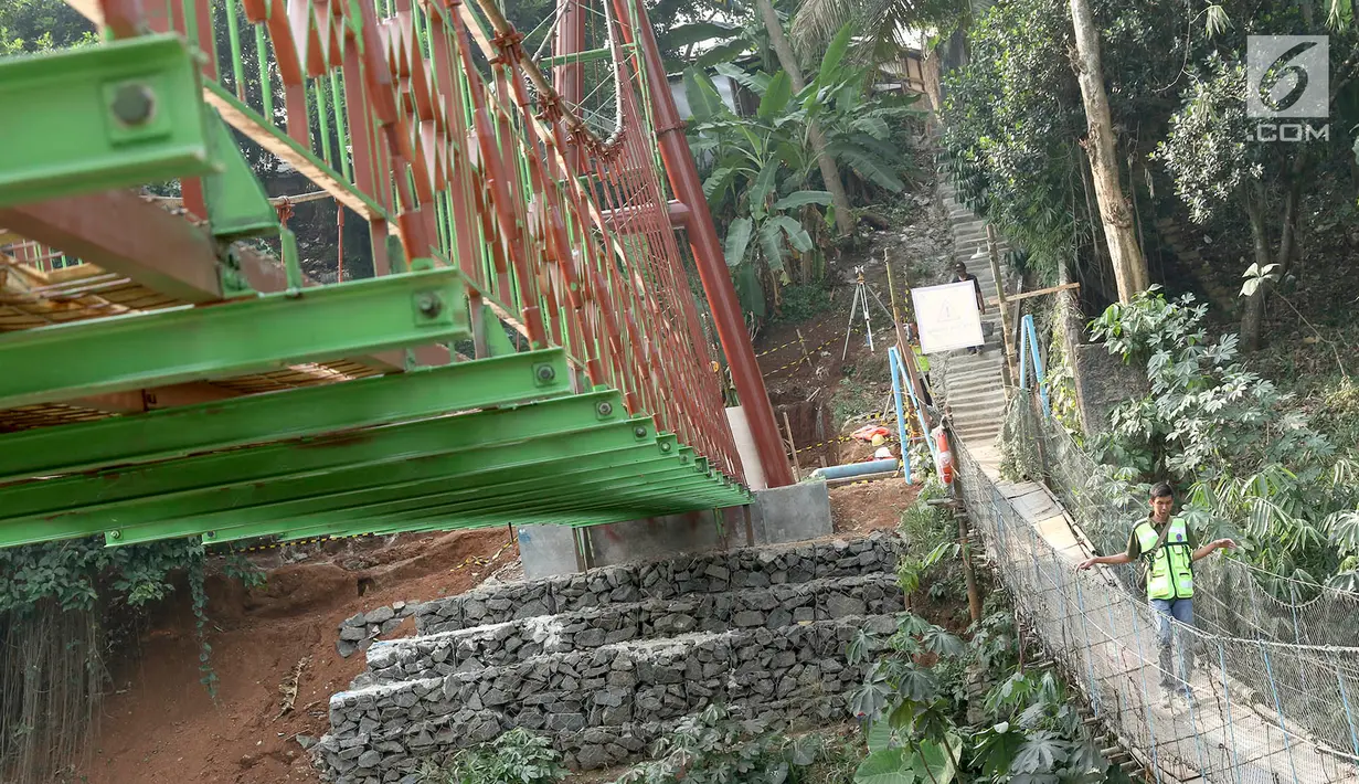 Pekerja berjalan di samping jembatan gantung yang diberi julukan Indiana Jones di Srengseng Sawah, Jagakarsa, Jakarta, Jumat (3/8). Pemprov DKI membangun jembatan Indiana Jones karena yang lama sudah tidak layak. (Liputan6.com/Immanuel Antonius)
