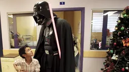 Seorang cosplayer berpakaian Darth Vader berbincang dengan seorang anak saat acara amal oleh El Salvador Star Wars fan club di Rumah Sakit Benjamin Bloom Anak Nasional di San Salvador, El Salvador (14/12). (REUTERS/Jose Cabezas)