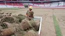 Pekerja memindahkan rumput yang ada di Stadion Utama Gelora Bung Karno (SUGBK) ke area panahan, Jakarta, Jumat (18/5). Pemindahan rumput seluas 7.500 meter akan menggunakan teknik sodding, yaitu menggulung rumput. (Liputan6.com/Johan Tallo)