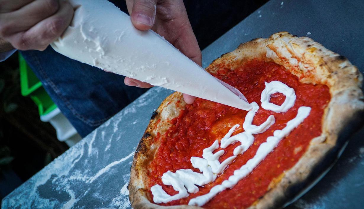 Koki menghias piza untuk merayakan penetapan seni memutar adonan piza masuk ke dalam "kebudayaan tak terlihat" milik UNESCO di Naples, Italia, 7 Desember 2017. Piza makanan asli benua Eropa yang lahir di kota Naples sekitar tahun 1720. (AP PHOTO)