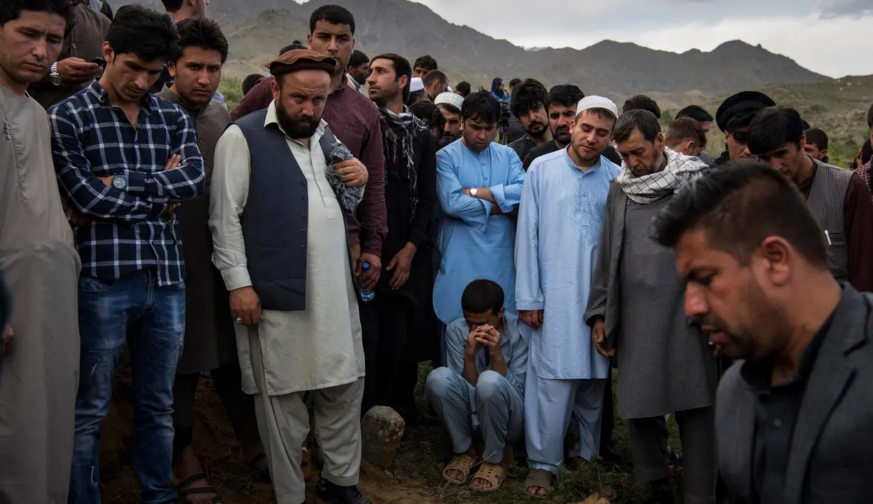 Teman dan kerabat berdoa di pemakaman kepala fotografer AFP Afghanistan Shah Marai Faizi di Gul Dara, Kabul (30/4). Para wartawan yang tiba untuk melaporkan ledakan pertama manjadi korban bom bunuh diri dalam serangan kedua. (Andrew Quilty / POOL / AFP)
