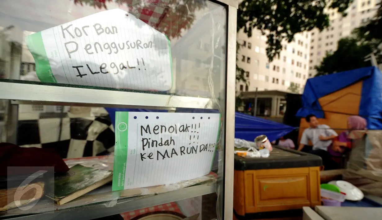 Tulisan penolakan masih terlihat diantara perabot rumah tangga di sisi Jalan Rawajati Barat, Jakarta, Jumat (2/9). Pasca penggusuran pemukiman bantaran rel kereta kawasan Rawajati, sejumlah warga masih memilih bertahan. (Liputan6.com/Helmi Fithriansyah)