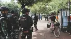 Seorang penjual minuman bersepeda melintas di depan personel Tentara Nasional Indonesia (TNI) yang berjaga di sebuah jalan setelah beberapa hari terjadi aksi unjuk rasa menentang kenaikan tunjangan anggota Dewan Perwakilan Rakyat (DPR), di Jakarta, Senin 1 September 2025. (AP Photo/Tatan Syuflana)