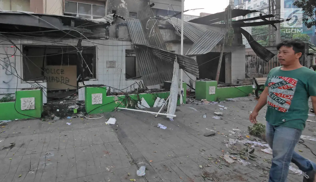 Pejalan kaki melintas di depan pos polisi yang rusak dibakar oleh massa di Jalan Agus Salim atau kawasan Sabang, Jakarta, Kamis (23/5/2019). Massa yang ricuh di depan Kantor Bawaslu, menghancurkan Pos Polisi Sabang serta membakar barang-barang yang ada di dalamnya. (Liputan6.com/Herman Zakharia)