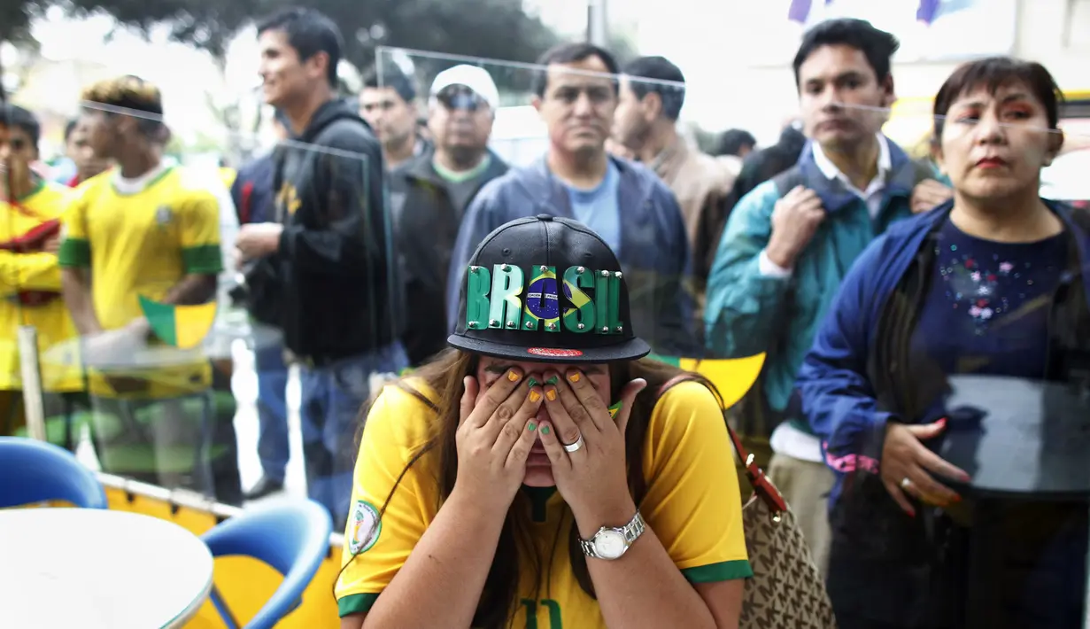 Seorang fans yang menyaksikan laga timnya, menangis setelah gawang Brasil kebobolan pada babak semifinal Piala Dunia 2014 melawan Jerman, Selasa (8/7/14). (REUTERS/Ueslei Marcelino)
