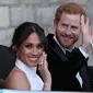 Pangeran Harry dan istrinya Meghan Markle tersenyum saat meninggalkan Kastil Windsor untuk ke acara resepsi dekat Frogmore House (19/5). Mobil yang dikenderai Pangeran Harry yaitu Jaguar Classic E-Type Concept Zero.  (AFP Photo/Pool/Steve Parsons)