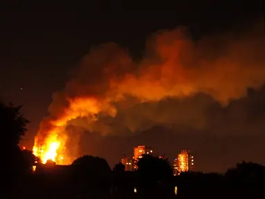 Kepulan asap menyelimuti sebuah apartemen bertingkat 24 lantai yang terbakar di London (14/6). Gedung Grenfell Tower yang terbakar itu berada di kompleks Lancester West Estate. (AFP PHOTO / Jonathan Kelly)
