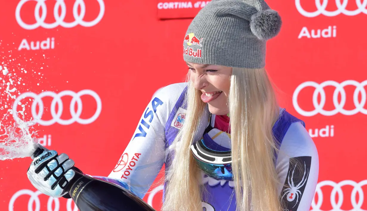 <p>Lindsey Vonn dari Amerika Serikat menyemprotkan sampanye saat merayakan kemenangannya pada kompetisi FIS Alpine World Cup Women's Downhill di Cortina d'Ampezzo, Pegunungan Alpen Italia (20/1). (AFP Photo/Tiziana Fabi)</p>