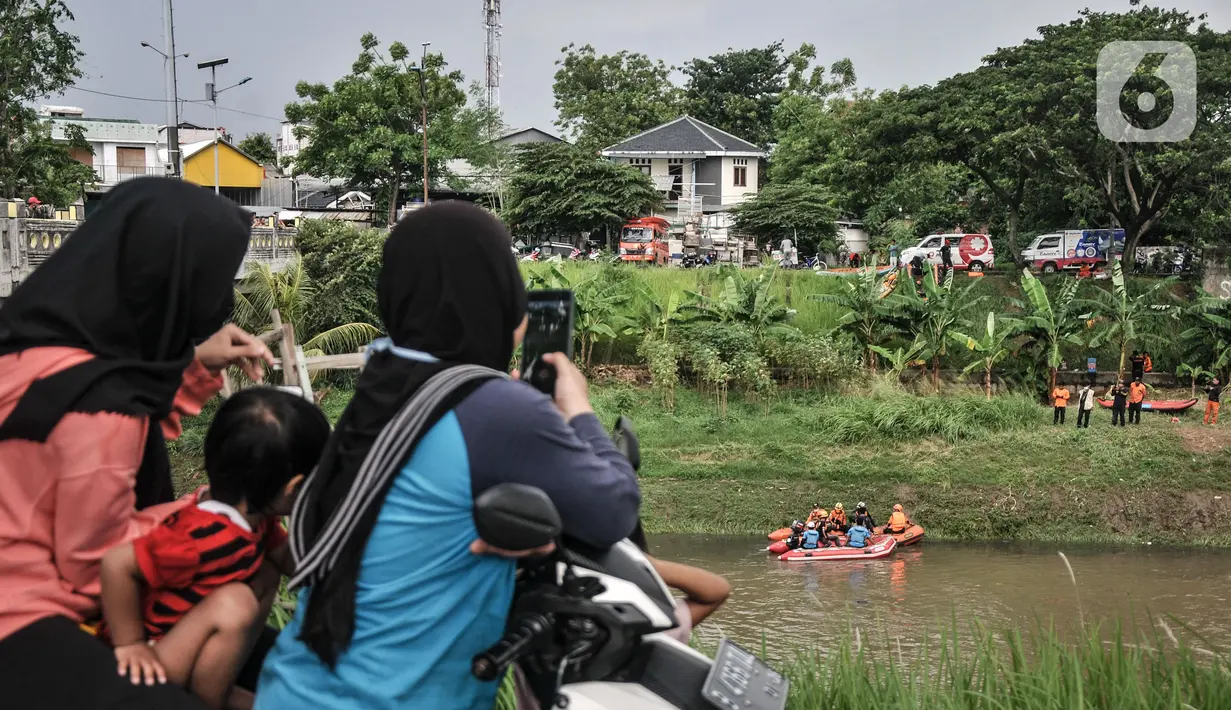 Warga menyaksikan pencarian korban tenggelam di Kanal Banjir Timur, Duren Sawit, Jakarta Timur, Selasa (2/11/2021). Sebelumnya ABP tenggelam dan hanyut terbawa arus saat bermain di saluran air saat hujan deras pada Senin (1/11) siang bersama ketiga temannya. (merdeka.com/Iqbal S. Nugroho)