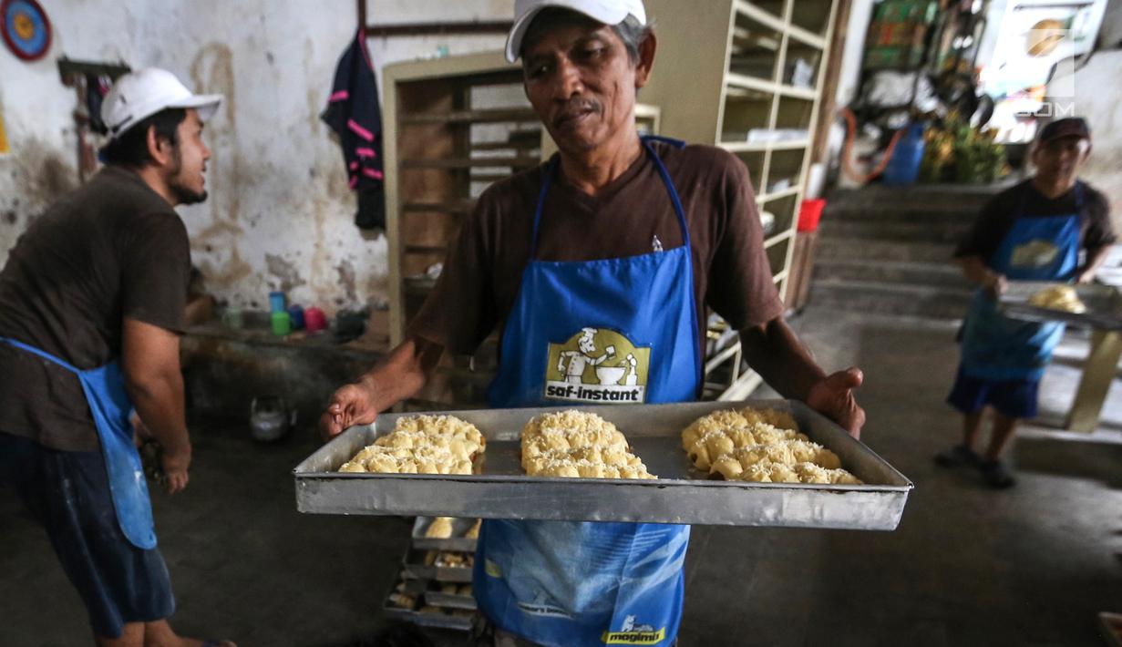 Karyawan membawa roti yang akan dipanggang ke dalam tungku di Toko Roti GO, Purwokerto, Jawa Tengah, Senin (22/4). Memasuki usia ke 121 tahun, toko roti yang berdiri sejak tahun 1898 ini dibuat mengunakan peralatan tradisional dan tanpa bahan pengawet. (Liputan6.com/Fery Pradolo)