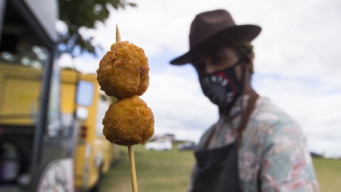 Seorang penjual yang mengenakan masker memperlihatkan bakso ayam goreng di Festival Ayam Goreng, Toronto, Kanada, 20 September 2020. Festival yang digelar di tengah pandemi COVID-19 tersebut berlangsung pada 19-20 September 2020 dengan menghadirkan sekitar 30 jenis ayam goreng. (Xinhua/Zou Zheng)