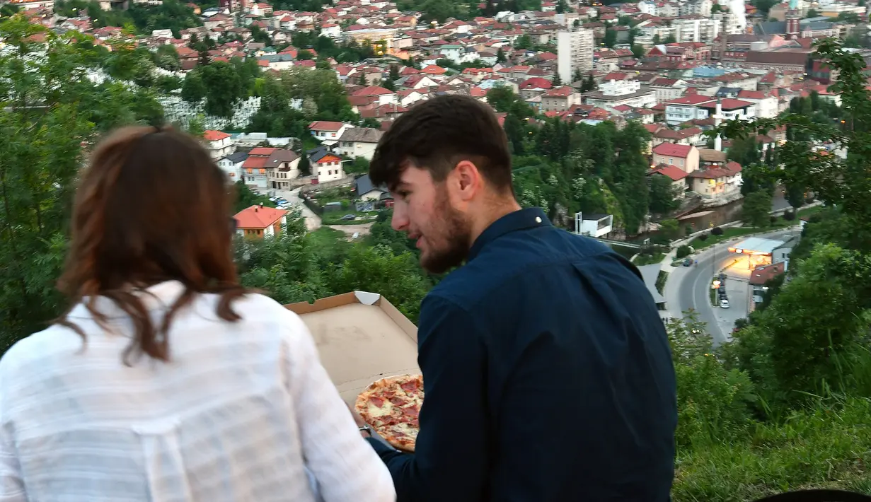 Pasangan Muslim Bosnia duduk menghadap ke kota sambil menunggu berbuka puasa pada hari pertama bulan suci Ramadan, di Sarajevo, (16/5). Muslim Bosnia mencapai sekitar 40 persen dari penduduk Bosnia 3,8 juta. (AFP Photo/Elvis Barukcic)