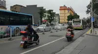 Pengandara skutik listrik di Changsa tak mengenakan helm saat berkendara (Gesit/Liputan6.com)