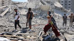 Kantor Media Pemerintah Gaza melaporkan agresi Israel yang kini memasuki hari ke-730 sejak dimulainya perang pada 7 Oktober 2023 telah menyebabkan lebih dari 67.000 warga Palestina gugur dan ratusan ribu lainnya luka-luka. Sementara itu, 90 persen wilayah Gaza nyaris rata dengan tanah akibat serangan udara dan darat Israel. Tampak dalam foto, seorang perempuan Palestina menggendong seorang anak sambil berjalan di antara reruntuhan dekat Menara Tiba yang runtuh beberapa saat setelah serangan Israel menargetkan gedung tinggi tersebut di Kota Gaza pada 10 September 2025. (Omar AL-QATTAA/AFP)