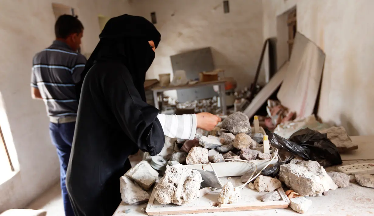 Seorang wanita bernama Safa al-Faqih memilih batu mulia yang masih mentah untuk dijadikan perhiasan dan batu cincin di tempat kerajinan di Sanaa, Yaman (18/4). (AFP/Mohammed Huwais)