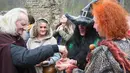 Seorang pria memberikan air kepada peserta yang hadir di acara Walpurgis Night atau Witches Night di Vilnius, Lithuania, Senin (1/5). Orang-orang yang hadir mengenakan atribut layaknya para penyihir. (AFP PHOTO / Petras Malukas)