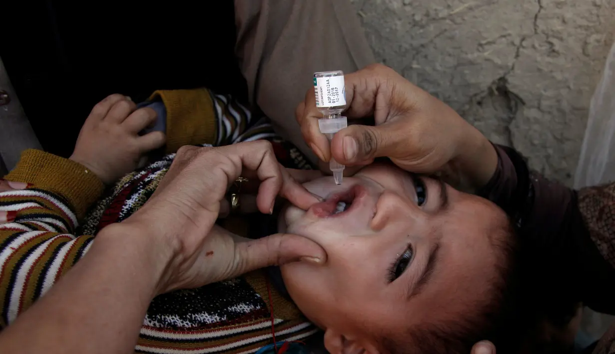 Seorang anak dipegangi orang tuanya saat petugas memberikan imunisasi polio di sepanjang jalan di Quetta, Pakistan, Senin (2/1). (REUTERS/Naseer Ahmed)