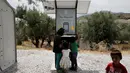 Anak-anak berdiri di dekat stasiun pengisian tenaga surya di kamp pengungsi di Pulau Lesbos, Yunani, 14 Juni 2016. Memanfaatkan teriknya matahari, stasiun pengisian baterai ponsel bertenaga surya ini bisa dinikmati pengungsi (REUTERS/Alkis Konstantinidis)