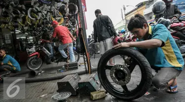 Montir sedang memperbaiki roda sepeda motor di bengkel kawasan Pasar Minggu, Jakarta, Kamis (30/6). Jelang Lebaran, pemudik motor mulai serbu jasa servis bengkel motor untuk persiapan mudik. (Liputan6.com/Yoppy Renato)