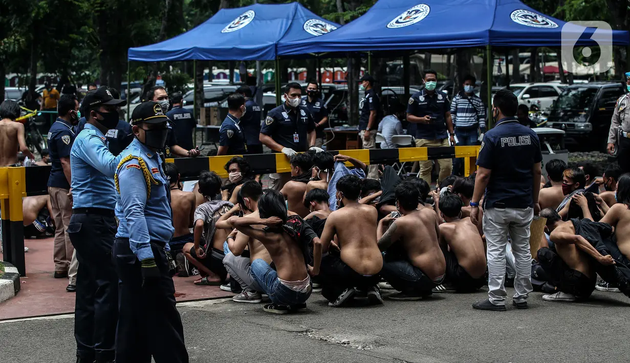 Sejumlah pemuda diamankan di Lapangan Futsal Gedung DPR, Kompleks, Parlemen, Senayan, Jakarta, Kamis (8/10/2020). Ratusan pemuda yang diamankan oleh petugas ini diduga hendak ikut demonstrasi menolak pengesahan Rancangan Undang-Undang Cipta Kerja menjadi UU di gedung DPR. (Liputan6.com/Johan Tallo)