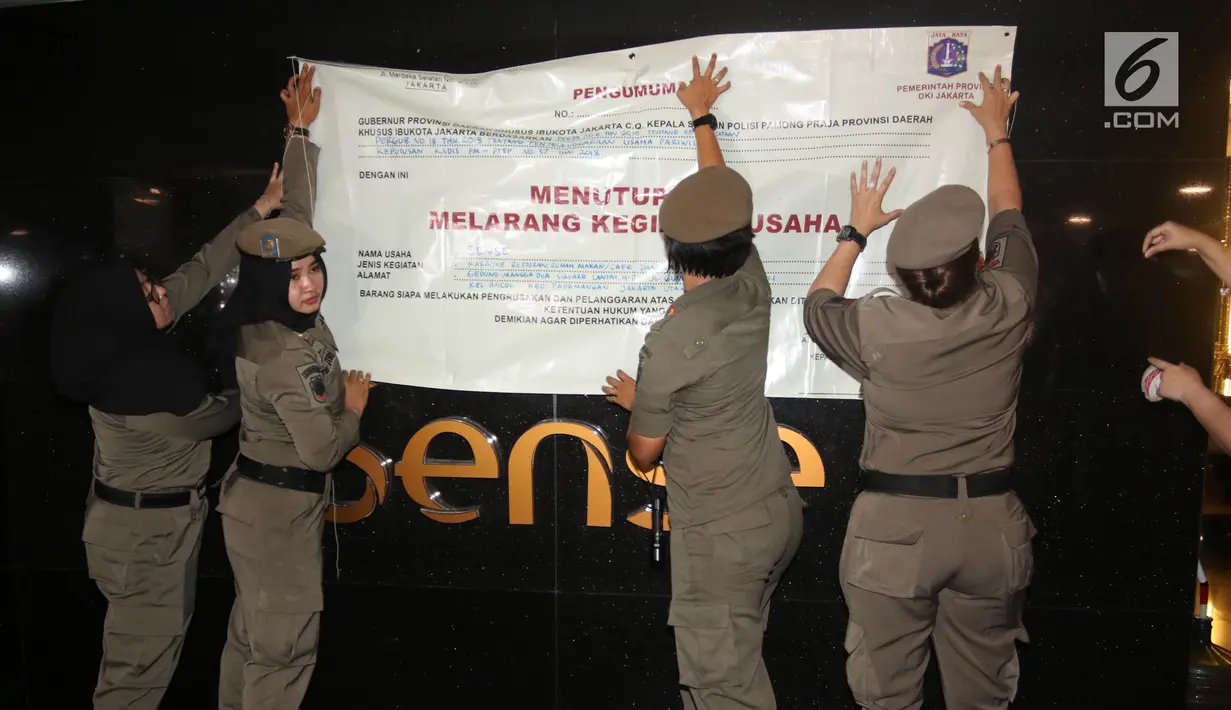 Petugas Satpol PP wanita memasang spanduk penyegelan untuk menutup Sense Karaoke di Mangga Dua Square, Jakarta, Kamis (19/4). Pemprov DKI Jakarta resmi menutup Sense Karaoke karena melanggar peraturan. (Liputan6.com/Arya Manggala)