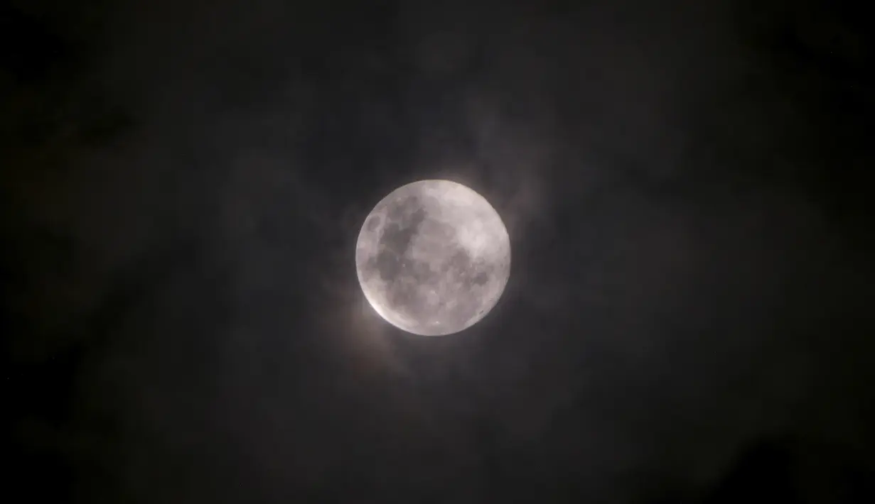 Awan tipis menutupi supermoon merah muda yang terlihat dari Jakarta, Indonesia, Selasa (7/4/2020). Fenomena dimana bulan berada pada titik terdekat dengan bumi ini merupakan penampakan supermoon terbesar di tahun 2020 .(BAY ISMOYO/AFP)