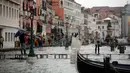 Seorang wanita mengambil gambar dari atas papan saat gelombang pasang menerjang Venesia, Italia, Selasa (12/11/2019). Venesia dilanda banjir akibat gelombang pasang setinggi 127 cm. (AP Photo/Luca Bruno)