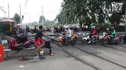 Pengendara motor melintas di perlintasan kereta api yang tidak berpalang pintu di kawasan Roxy, Jakarta, Rabu (21/3). Akhirnya antara warga dan petugas menyepakati untuk membuka celah selebar dua meter di lokasi tersebut. (Liputan6.com/Arya Manggala)