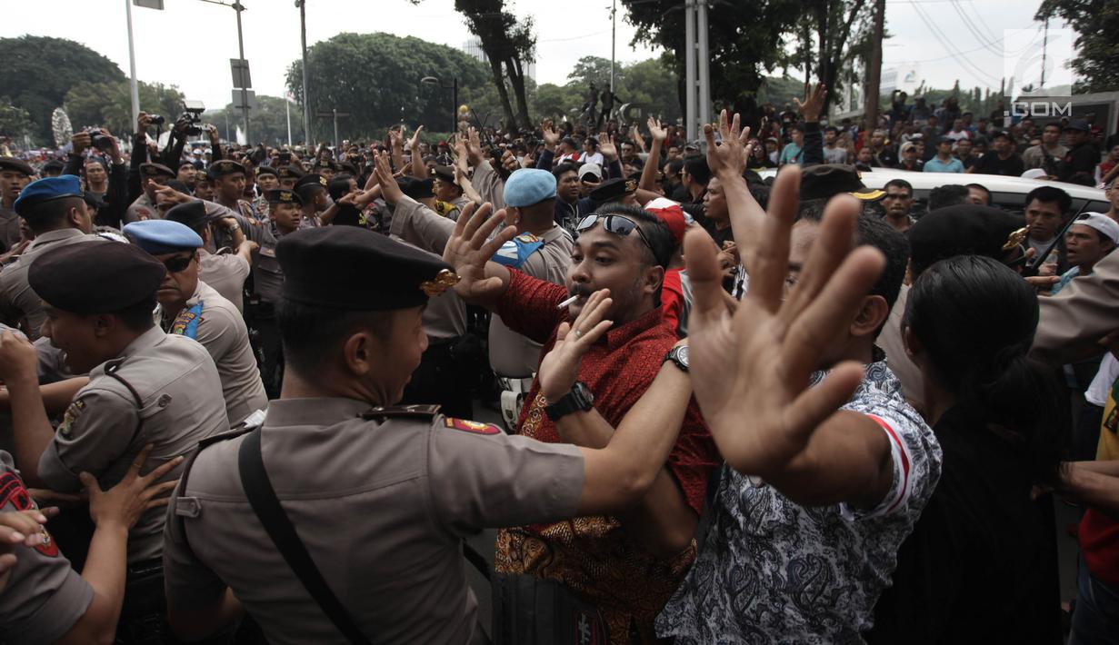 Demonstran driver online saling dorong dengan polisi saat unjuk rasa di depan Istana Negara, Jakarta, Rabu (14/2). Aksi pemberhentian mobil taksi online yang masih beroperasi oleh demonstran sempat membuat situasi tegang. (Liputan6.com/Arya Manggala)